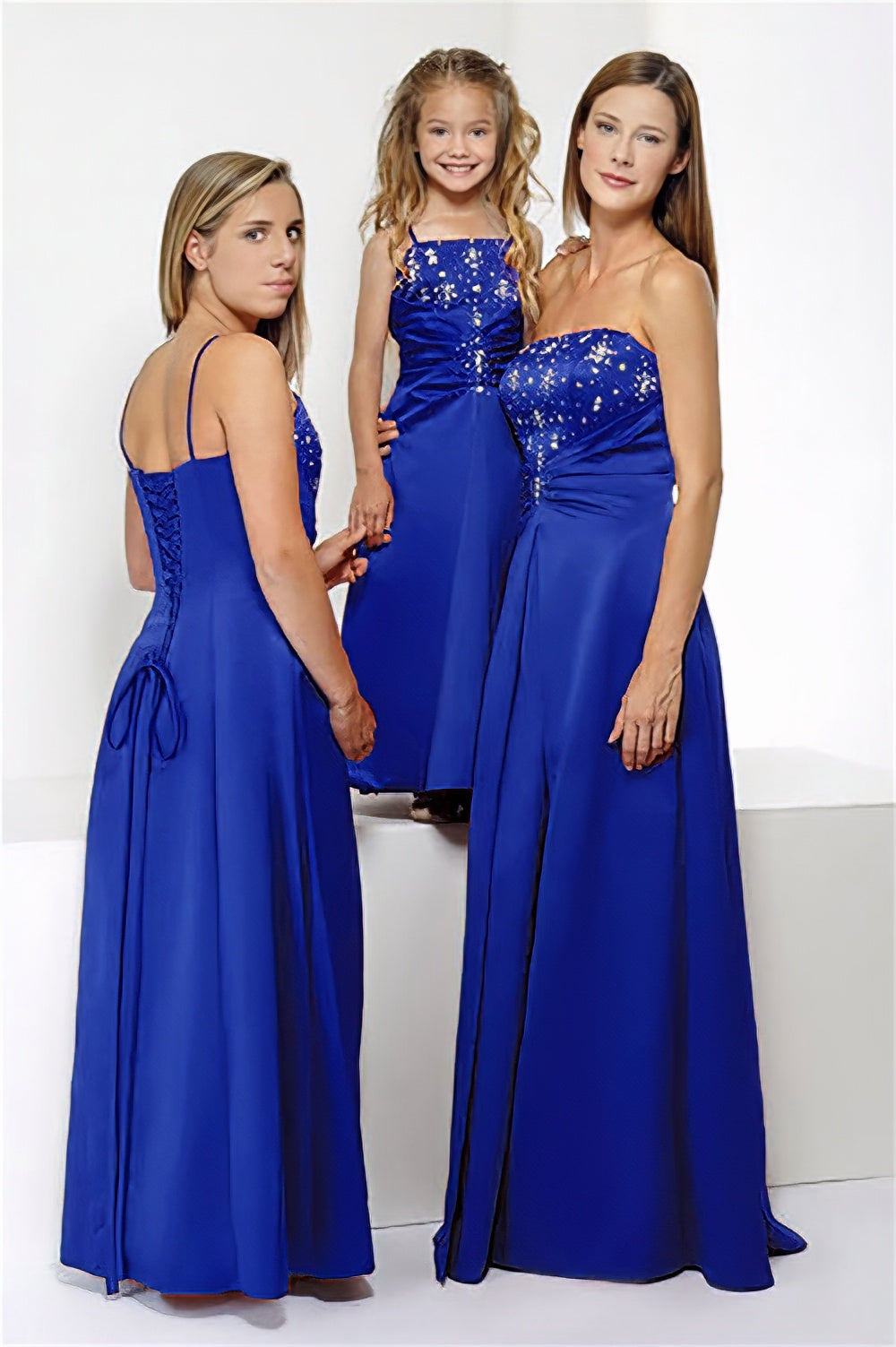 3 models wearing the same full length long royal blue satin corset a-line bridesmaid dress with sequin detail, shown in strapless and spaghetti strap styles, multi-colour options